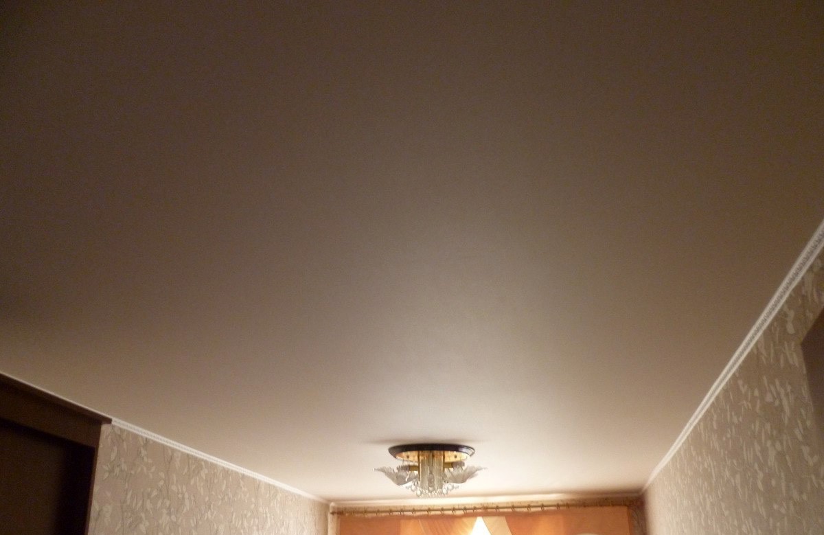 Коричневый матовый натяжной потолок с люстрой в комнате