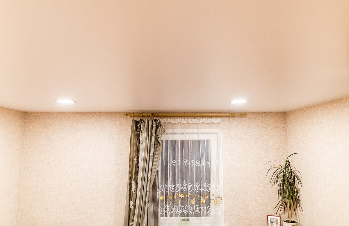 Кремовый матовый натяжной потолок со светильниками в комнате