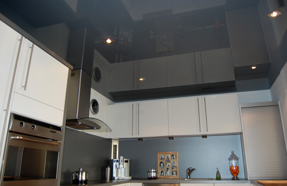 Глянцевый натяжной потолок цвета графита со светильниками в кухне