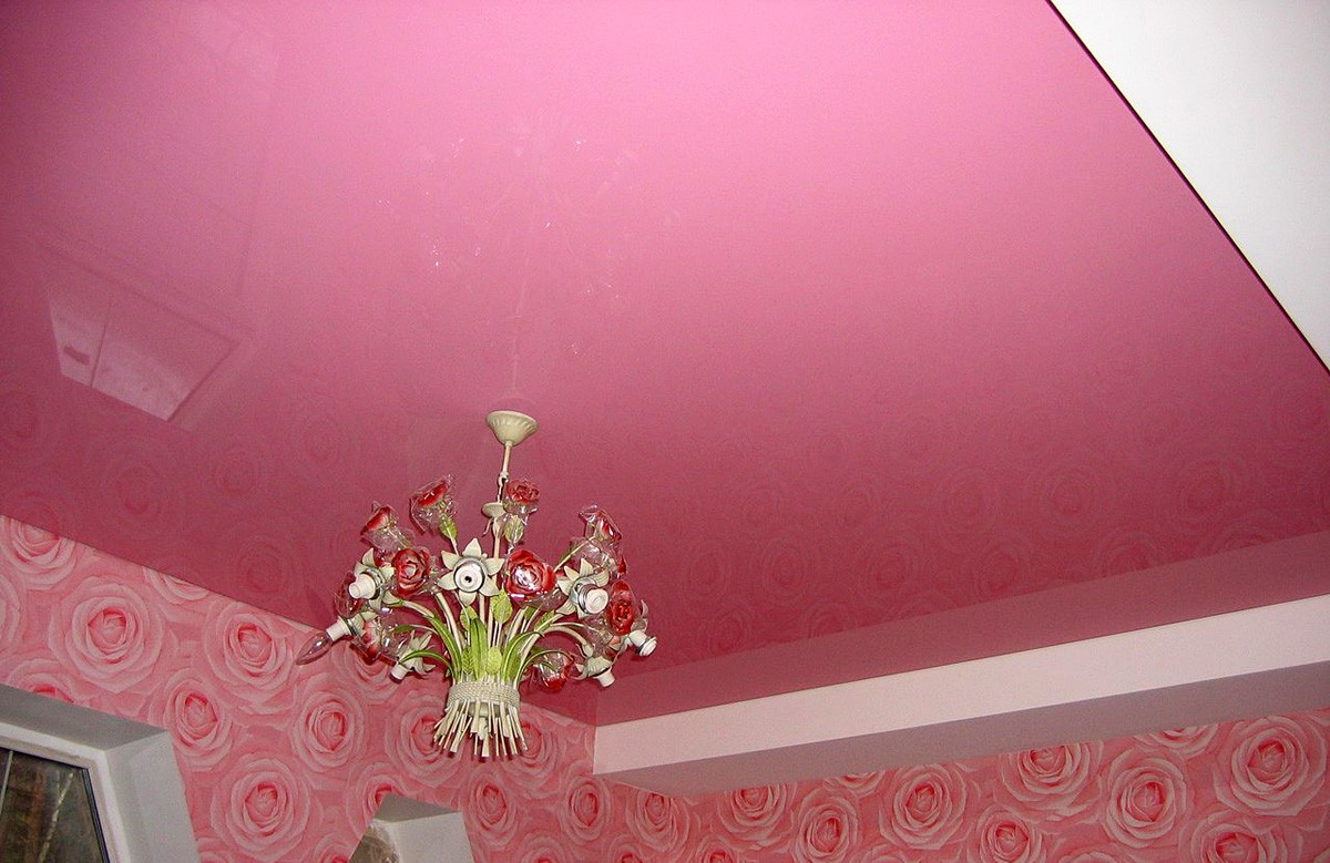 Розовый глянцевый натяжной потолок с люстрой