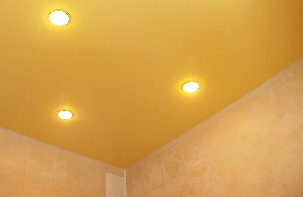 Жёлтый матовый натяжной потолок в ванной с тремя светильниками