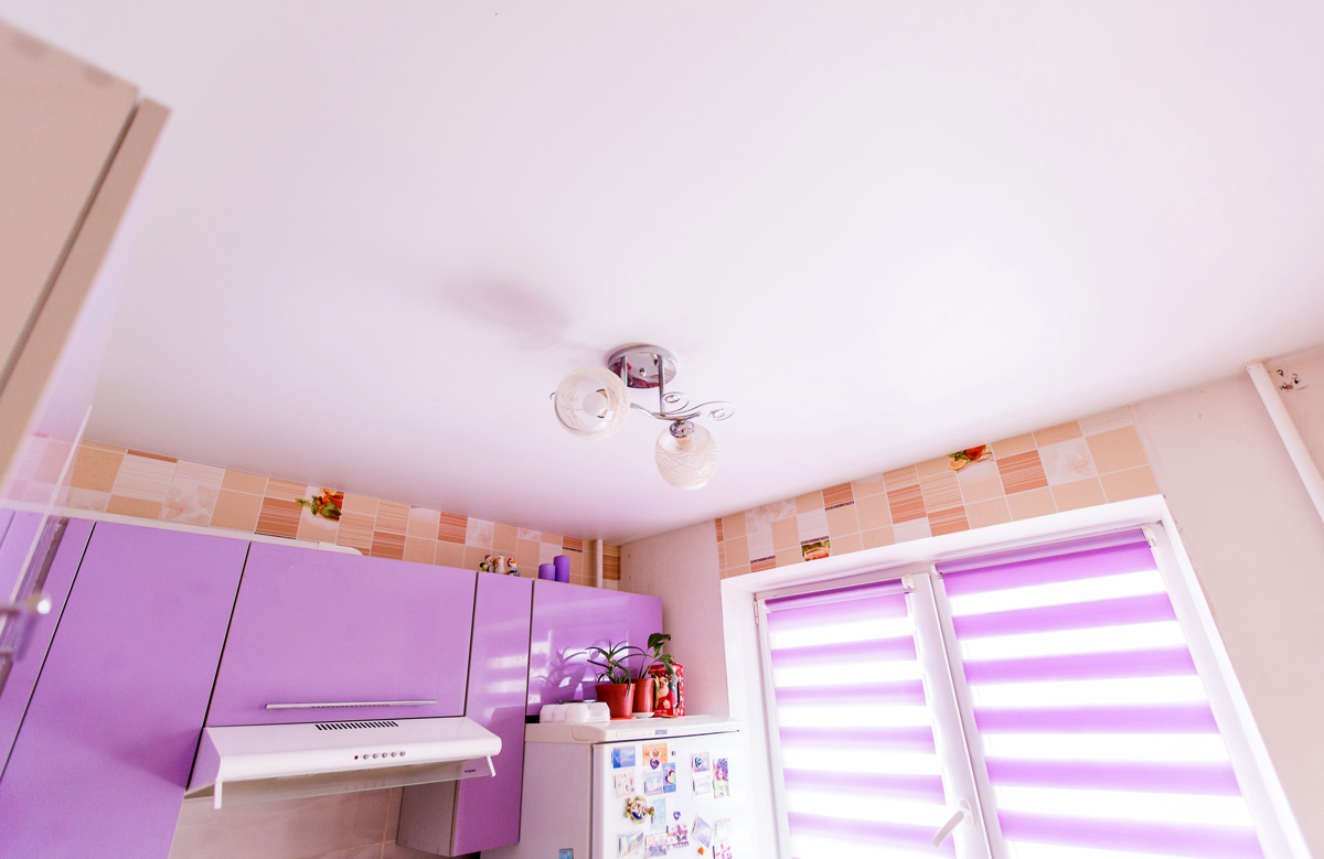 Белый матовый натяжной потолок в кухне с люстрой